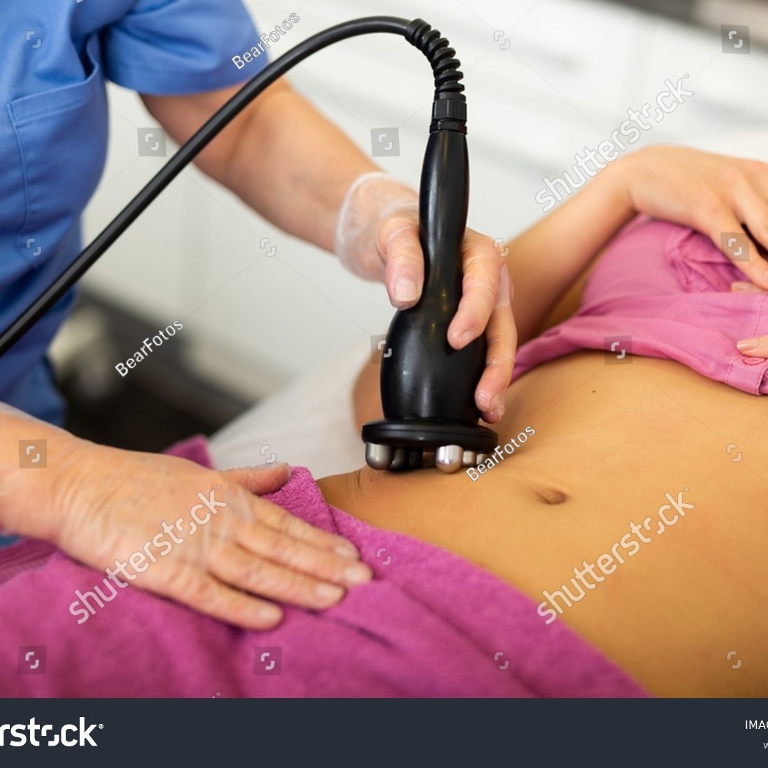 stock-photo-cosmetology-doctor-makes-a-young-female-client-lying-on-the-couch-a-vacuum-massage-of-the-abdomen-2256756659